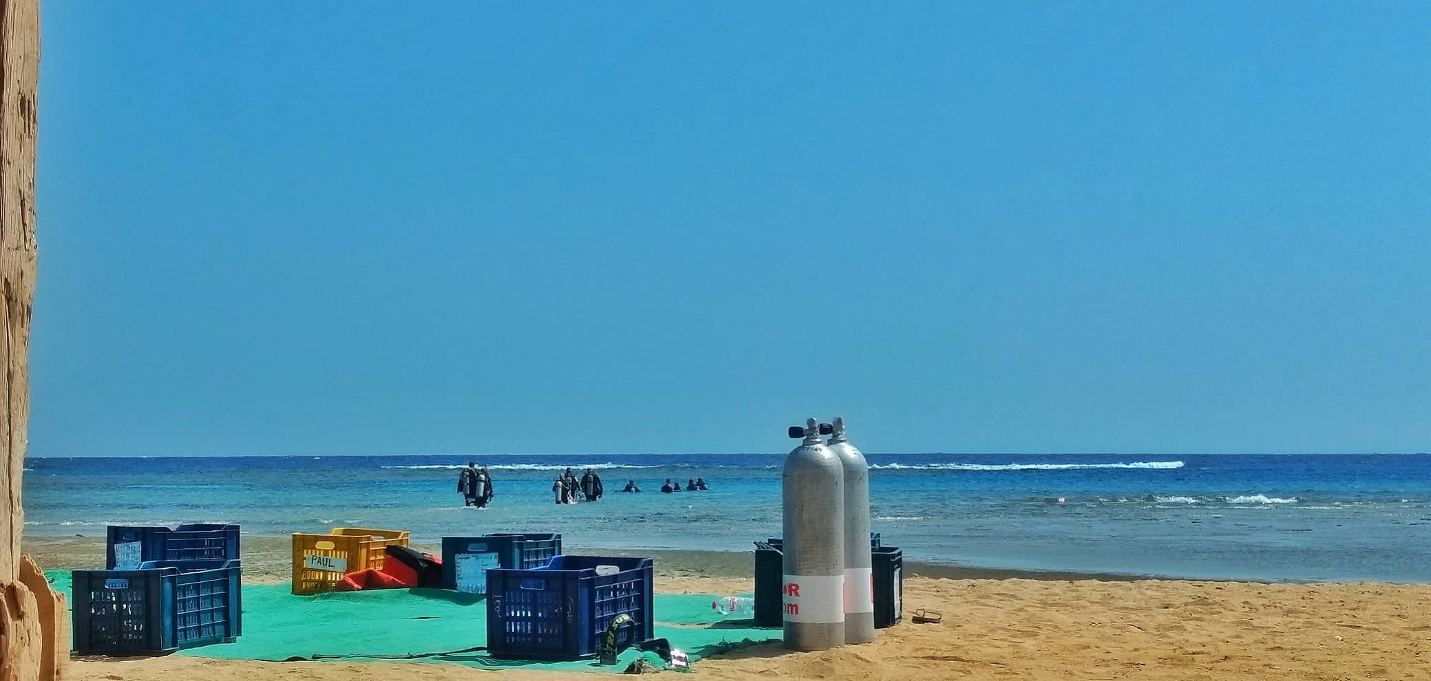 © SeaHorse Diving Club | Air tanks on the beach and scuba divers entering the water in Abu Ghusun dive site | Diving center in Marsa Alam, Egypt